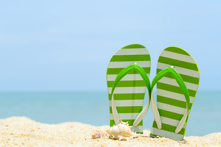 Pair of green striped sandal and seashell on the beachの写真素材