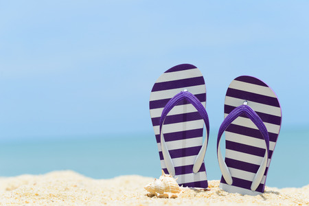 Pair of purple striped sandal and seashell on the beachの写真素材
