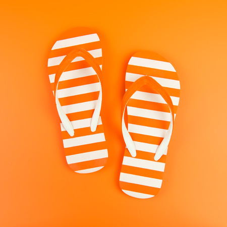 Pair of orange striped flip flop on orange backgroundの写真素材