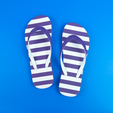 Pair of purple striped flip flop on blue backgroundの写真素材