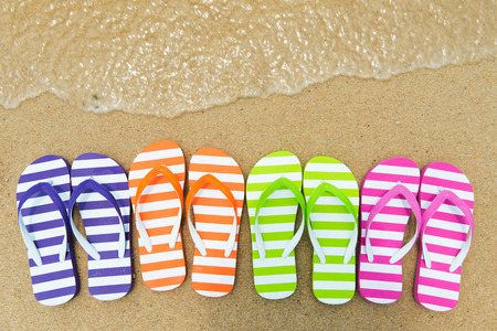 Close up of multicolor flip flips on sandの写真素材