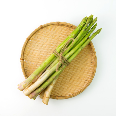 Bundle of fresh asparagus on bamboo tray basketの写真素材