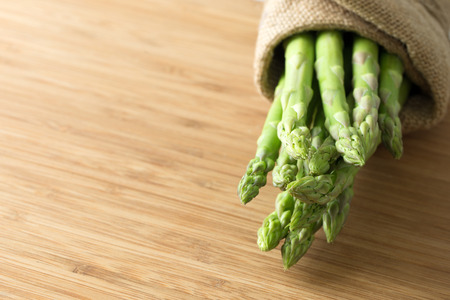 Bundle of fresh asparagus on wooden chopping boardの写真素材