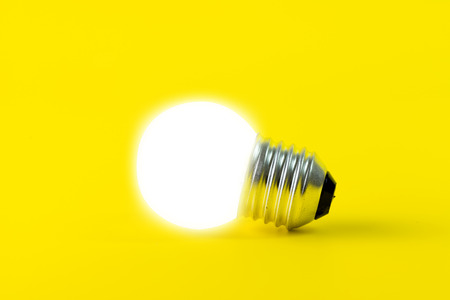 Glowing light bulb isolated on yellow backgroundの写真素材