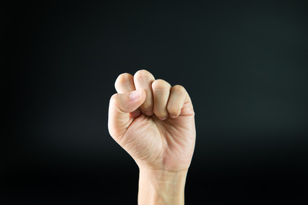 Male's hand with clenched fist on black backgroundの写真素材