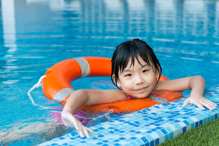 Little Asian girl with orange water ring in swimming poolの写真素材
