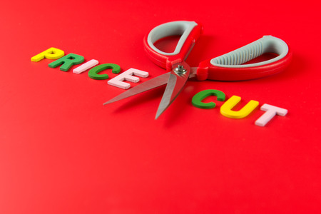 Price cut concept with pair of scissors between the word price and cut on red backgroundの写真素材