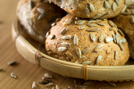 Close up of whole wheat buns with sunflower seeds on chopboardの写真素材
