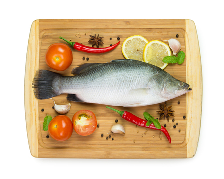 Fresh raw fish with ingredients on chopboardの写真素材