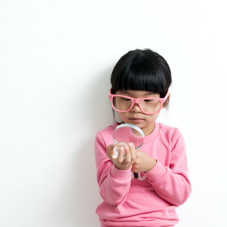 Little Asian girl looking at the crystal globe with magnifying glassの写真素材