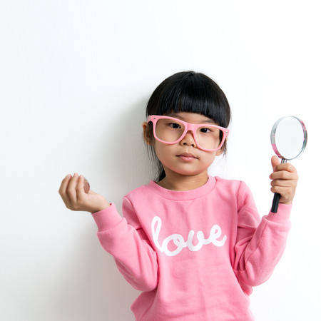 Little Asian girl looking at the crystal globe with magnifying glassの写真素材