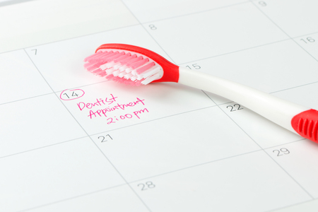 Red toothbrush on dentist appointment reminder on a calendarの写真素材