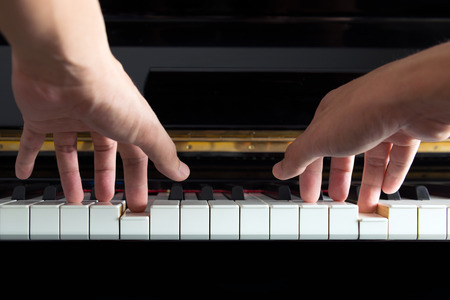 Male musician's hands playing music on pianoの写真素材