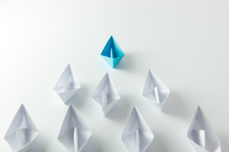 Leadership concept with blue paper ship leading among whiteの写真素材