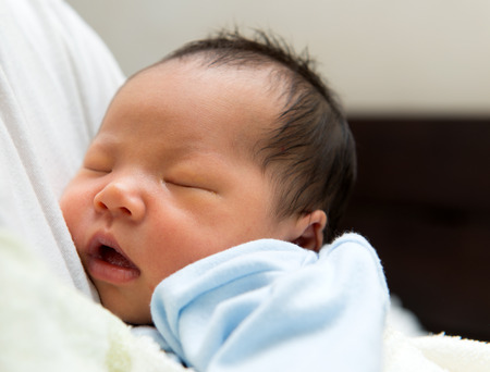 Asian newborn baby wear in blue cloth and is nappingの写真素材