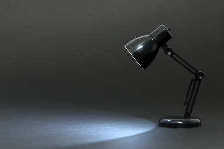 Table lamp illuminates in the dark background, with copy spaceの写真素材