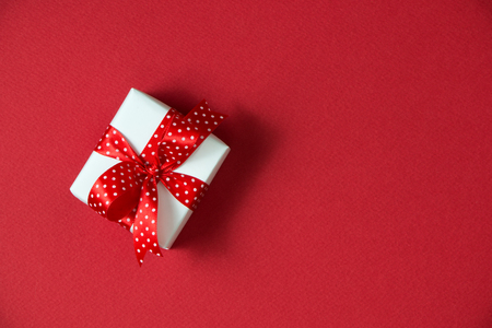 White gift boxes with red ribbon viewed from top isolated on red color backgroundの写真素材