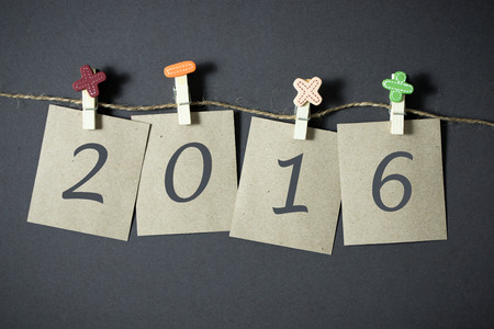 Paper showing new year 2016 hanging on rope over grey background