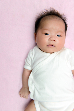 Portrait of Asian baby on pink backgroundの写真素材