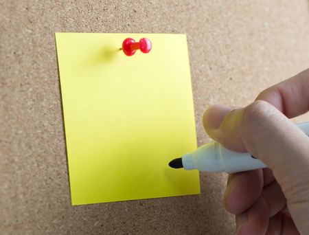 Blank yellow sticky note with hand hold a marker penの写真素材