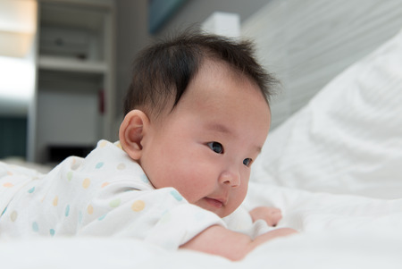 Portrait of Asian baby crawling on bedの写真素材