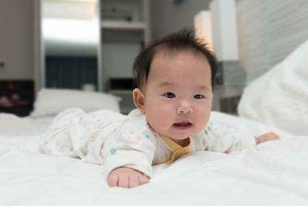 Portrait of Asian baby crawling on bedの写真素材