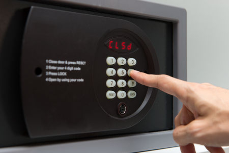 Hand press key on black safety box to closeの写真素材