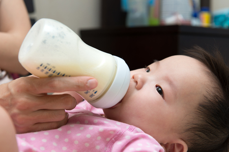 Mother feeding baby with milk from a bottleの写真素材