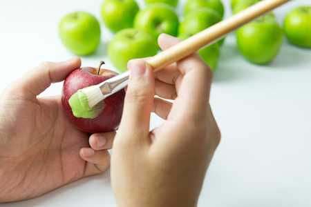Concept of assimilation by painting red apple into green colorの写真素材