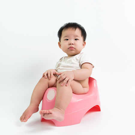 Asian baby sitting on potty over white backgroundの写真素材