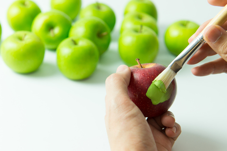 Concept of assimilation by painting red apple into green colorの写真素材