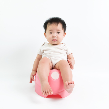 Asian baby sitting on potty over white backgroundの写真素材