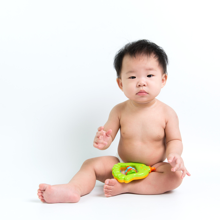 Asian baby wearing diaper sitting up on white backgroundの写真素材