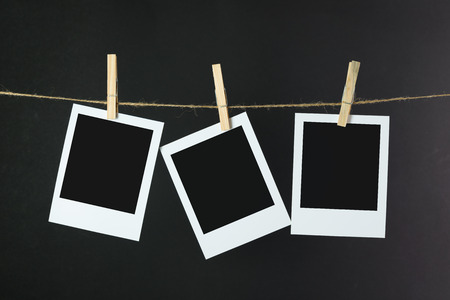 Blank photos hanging on rope over black backgroundの写真素材