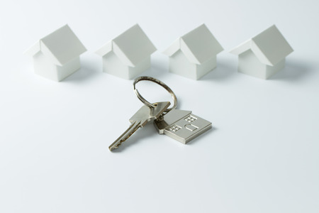 House key in front of a row of miniature white housesの写真素材
