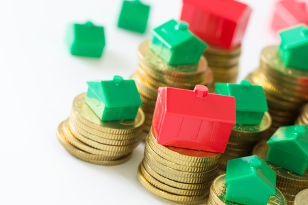 Close up of model houses on stacks of gold coinsの写真素材