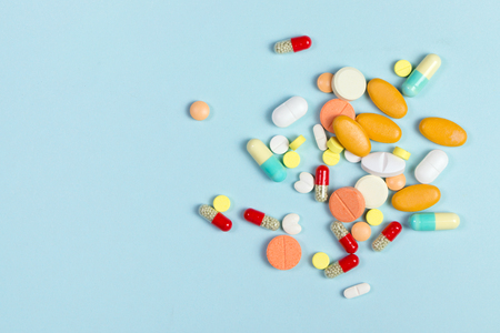 Assorted pharmaceutical medicine pills, tablets and capsules over blue backgroundの写真素材