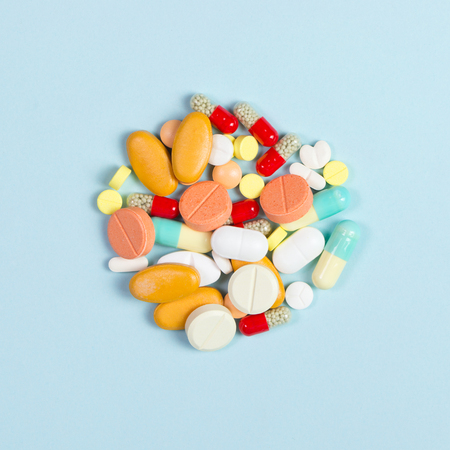 Assorted pharmaceutical medicine pills, tablets and capsules over blue backgroundの写真素材