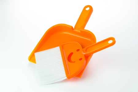 Small orange broom and dustpan over white backgroundの写真素材