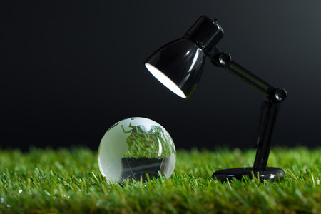 Table lamp lights up crystal globe on the grassの写真素材