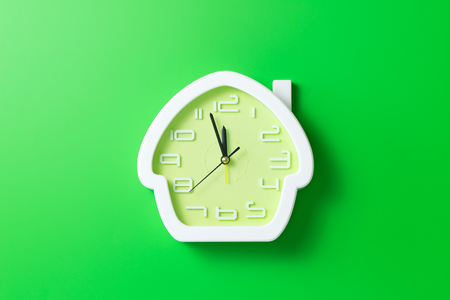 House shaped alarm clock isolated in green backgroundの写真素材