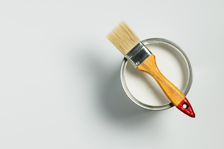 Paint brush placed on top of a can filled with white paintの写真素材