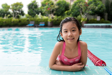 Little Asian girl in the sunny swimming poolの写真素材