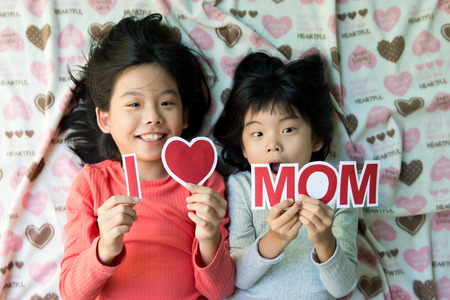 Two Asian kids holding I Love Mom wording for happy mother's day themeの写真素材
