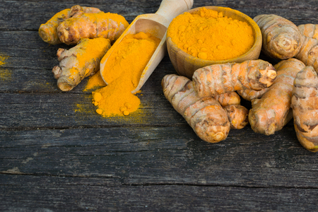 Fresh turmeric roots and turmeric powder on wood backgroundの写真素材