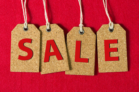 Close up of sale letters on tags over red backgroundの写真素材