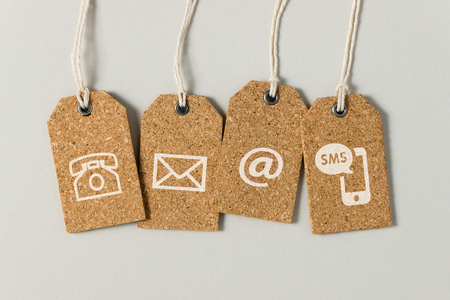 Website contact us icons on brown tags over grey backgroundの写真素材