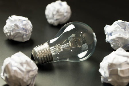 Close up of light bulb among crumpled paper ball on black backgroundの写真素材