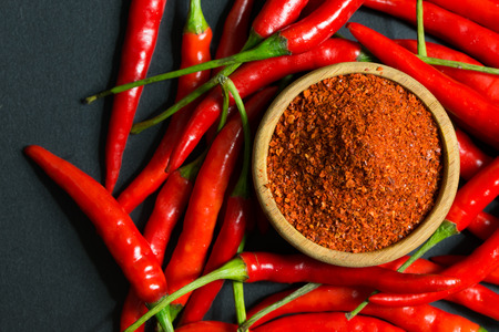 Red chili peppers and chili flakes on black backgroundの写真素材
