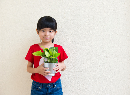 Portrait of little Asian girl holding potted plantの写真素材